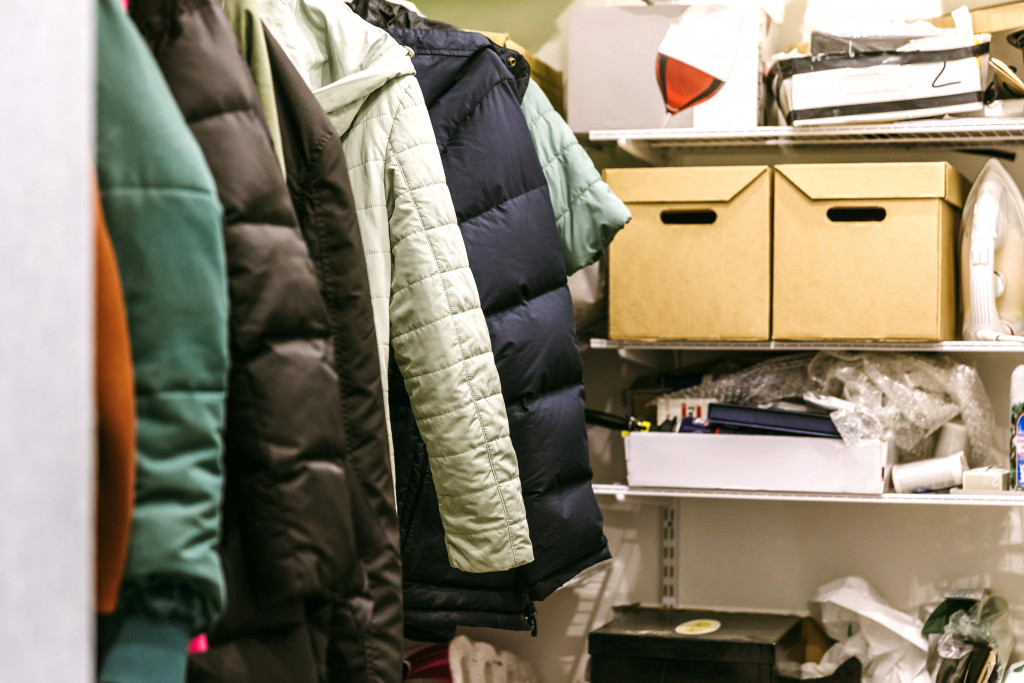 A small walk-in closet cluttered with winter clothes and other unused items