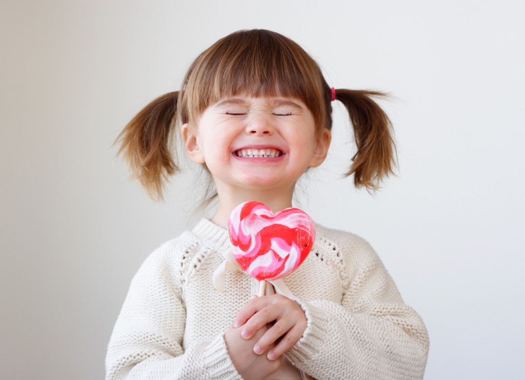 little girl holding a big heart shaped lollipop
